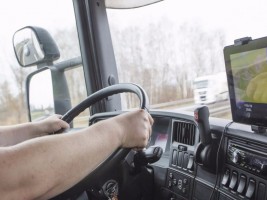 Male arms driving a truck on the road