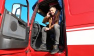 Driver talking by mobile phone while sitting in cabin of big modern truck