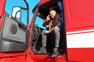 Driver talking by mobile phone while sitting in cabin of big modern truck