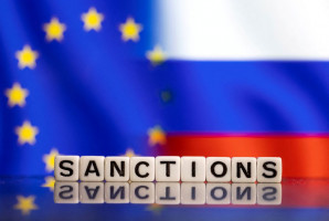Illustration shows letters arranged to read "Sanctions" in front of EU and Russia's flag colors
